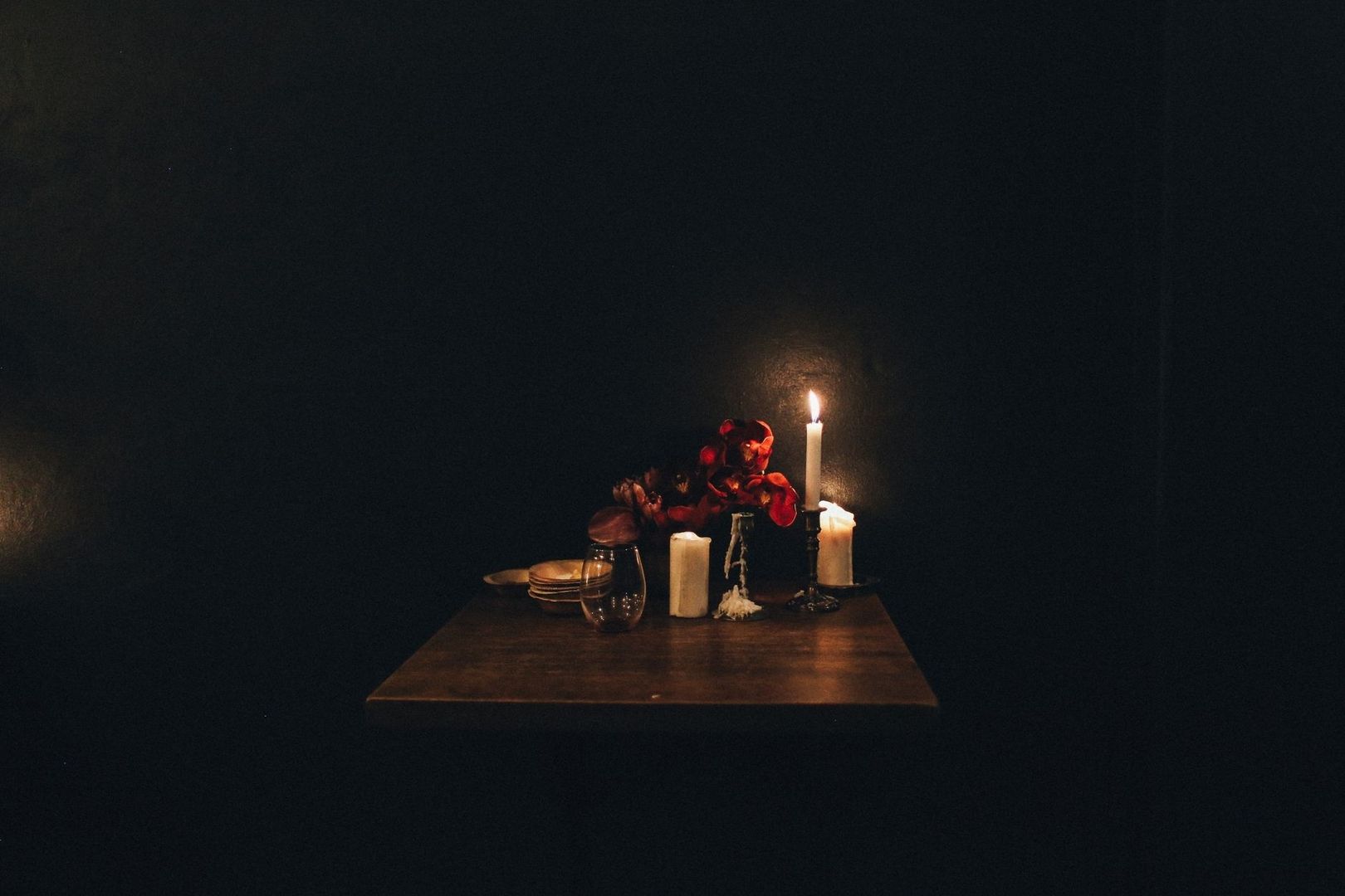 Table dressée dans la pénombre, éclairée par des bougies et des fleurs