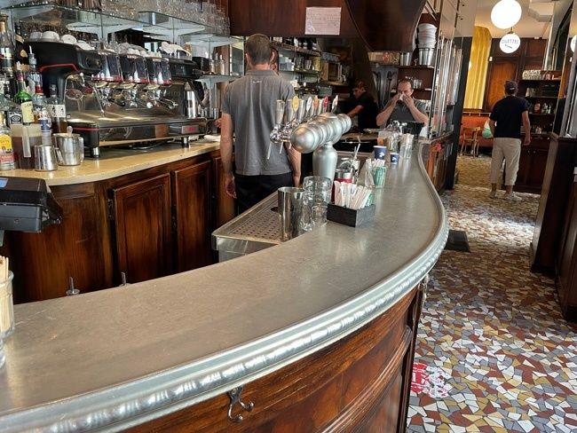 Comptoir en zinc courbé dans un bistrot parisien animé
