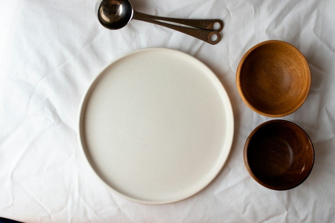 Assiette en céramique claire et bols en bois sur un linge blanc