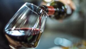 Vin rouge versé d’une bouteille dans un verre à dégustation