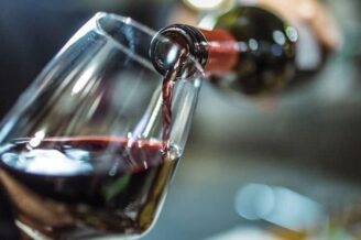 Vin rouge versé d’une bouteille dans un verre à dégustation