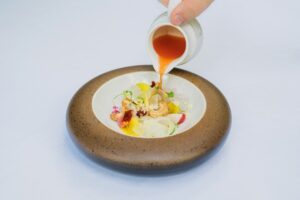 Sauce versée sur un plat raffiné dans un bol en céramique artisanale