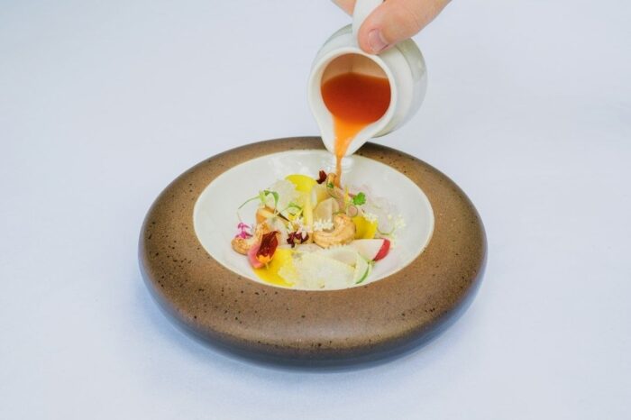 Sauce versée sur un plat raffiné dans un bol en céramique artisanale